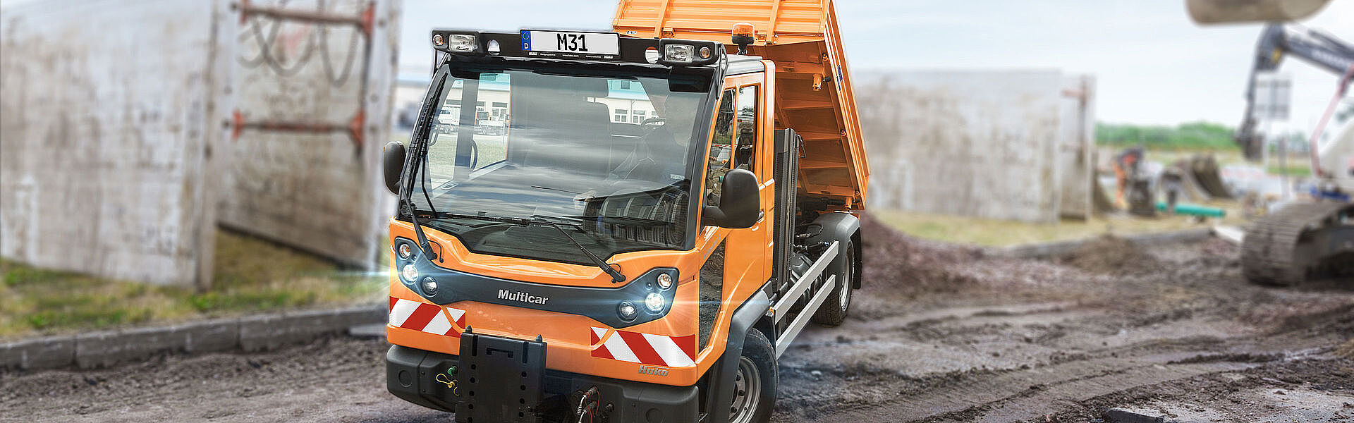 Kommunaler Lasten- und Geräteträger beim Entladen auf einer Baustelle.