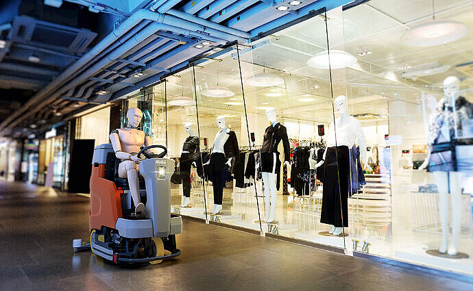 Reinigungsgerät beim Scheuersaugen vor einem Geschäft im Einkaufszentrum.